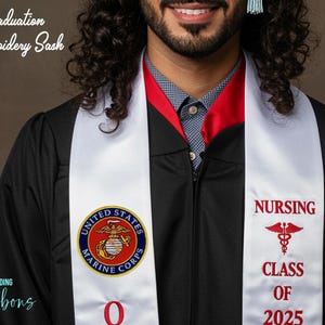 May include: White graduation sash with red embroidery. The left side features the United States Marine Corps emblem. The right side says "Nursing" with a caduceus symbol and "Class of 2025".