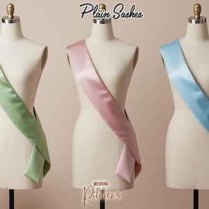 May include: Three satin sashes in pastel colors: light green, pink, and light blue. The sashes are draped over dress forms. The text "Plain Sashes" and "Wedding Ribbons" are visible.