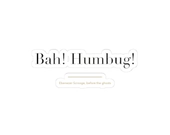 May include: A die-cut sticker featuring the black text Bah! Humbug! in a serif font. Below the main text is a thin horizontal line and the smaller light brown text Ebenezer Scrooge, before the ghosts, all on a white background.