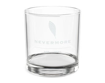 May include: A clear glass tumbler featuring an etched design of a single feather positioned above the word NEVERMORE. Below the text, a thin horizontal line separates the word from the smaller etched text reading POE 1845 at the base.