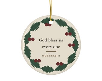 May include: A round ceramic ornament with a gold hanging string. The cream-coloured surface features a dark green holly leaf wreath with red berries. The text reads "God bless us every one" followed by the Roman numeral "MDCCCXLIII" in brown.