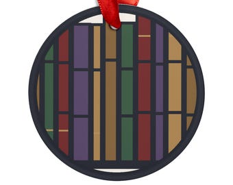 May include: A round ceramic ornament featuring a graphic pattern of vertical rectangular blocks in shades of dark green, deep red, purple, and tan, separated by thin black lines. A red ribbon is attached to the top for hanging purposes.
