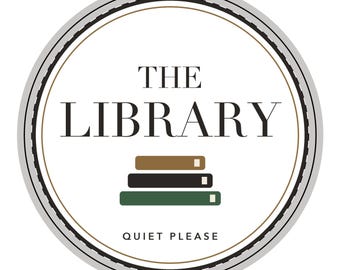 May include: A circular sticker or sign featuring a white background with a grey and black border. The text THE LIBRARY is centred in black, with three stacked books in tan, dark brown, and green below it. The text QUIET PLEASE is at the bottom.