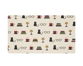 May include: A rectangular mat with a cream-coloured background featuring a repeating pattern of black cat silhouettes, round eyeglasses, stacks of colourful books, brown table lamps, and red coffee mugs with steam rising from them.