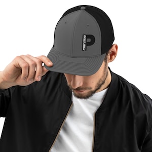 Puede incluir: Una gorra de camionero gris y negra con una "P" bordada en negro y el texto "POWER STROKE" en la parte delantera.