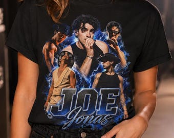 Op de afbeelding: Een zwart t-shirt met korte mouwen en een grafische print van Joe Jonas in verschillende poses, omringd door blauwe bliksemeffecten. Het ontwerp bevat de tekst JOE JONAS in een vet, gestileerd blauw lettertype onderaan de afbeelding.