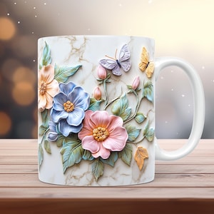 Peut inclure: Une tasse en céramique blanche avec un motif floral 3D. Le motif présente des fleurs roses, bleues et jaunes avec des feuilles vertes et des papillons. La tasse a une poignée blanche.