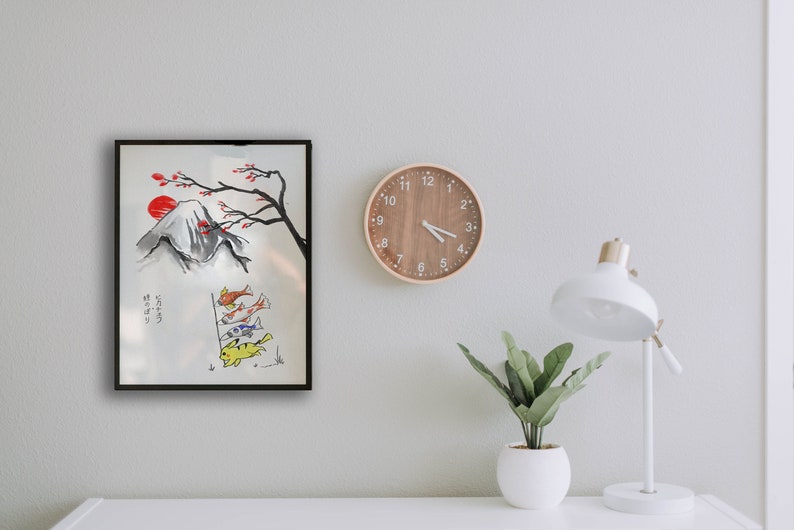 K&ouml;nnte beinhalten: Ein schwarzer gerahmtes Aquarellbild des Mount Fuji mit einer roten Sonne, die hinter ihm untergeht. Ein Kirschbl&uuml;tenzweig mit rosa Bl&uuml;ten h&auml;ngt &uuml;ber dem Berg. F&uuml;nf bunte Fische fliegen in der Luft unterhalb des Berges. Die japanischen Schriftzeichen "こいのぼり" sind in der linken unteren Ecke des Bildes geschrieben.
