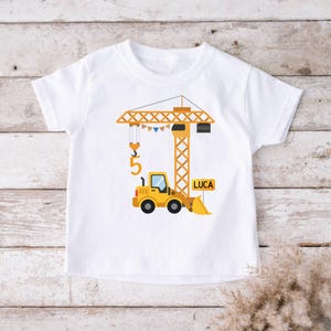 Könnte beinhalten: Weißes T-Shirt mit einem gelben Baukran und einem gelben Frontlader. Die Zahl "5" und der Name "LUCA" sind ebenfalls abgebildet. Das Design ist wahrscheinlich für einen Kindergeburtstag.
