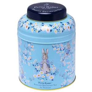 Può includere: Una scatola di latta blu con un motivo floreale bianco e giallo con Peter Rabbit. La scatola ha un coperchio blu con il testo "The World of Peter Rabbit" e "English Breakfast Tea". La parte inferiore della scatola dice "Peter Rabbit English Breakfast Tea 80 Teabags".