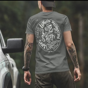 Peut inclure: Un t-shirt gris foncé avec un graphique blanc d'une pieuvre et le texte "Their Limited Imagination Can't Constrain You".