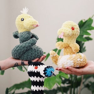 May include: Three crocheted stuffed toys in the shape of snakes. One is green, one is yellow and white, and one is black and white.