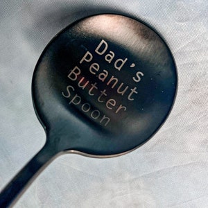 May include: A black metal spoon with the words "Dad's peanut butter spoon" engraved on the bowl.