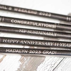 May include: Five stainless steel drinking straws with different engraved messages. The messages are "Girl's Weekend 2023", "Congratulations!", "Sip Sustainably", "Happy Anniversary 11 Years", and "Madalyn 2023 Grad!"