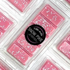 May include: Pink wax melts with white speckles in a clear plastic container. A black circular label reads "Snow Pixie" with "little-melts" and "Handpoured Soy Wax Melts" in white text.