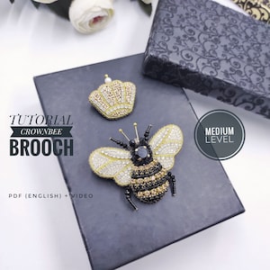 Könnte beinhalten: Eine Anleitung zum Herstellen einer Perlen-Kronen-Bienen-Brosche. Die Brosche ist aus schwarzen, goldenen und weißen Perlen gefertigt. Die Anleitung beinhaltet ein PDF in englischer Sprache und ein Video. Der Schwierigkeitsgrad ist mittel.