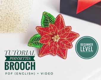 Könnte beinhalten: Eine handgefertigte Poinsettia-Brosche mit roten und goldenen Perlen, grünen Perlenblättern und einem goldenen Mittelteil. Die Brosche ist Teil eines Tutorials mit dem Text "Tutorial Poinsettia Brooch PDF (English) + Video" und "Beginner Level".