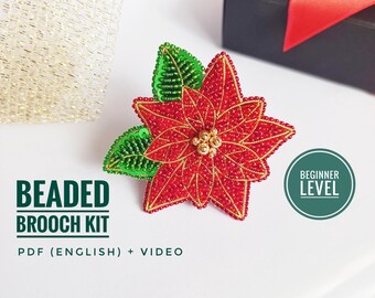 Könnte beinhalten: Ein Perlen-Poinsettia-Broschen-Set mit roten und goldenen Perlen, grünen Blättern und einem goldenen Zentrum. Das Bild enthält den Text "Beaded Brooch Kit" und "Beginner Level". Das Set enthält ein PDF auf Englisch und ein Video.