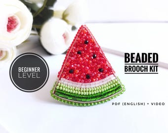 Könnte beinhalten: Ein Perlen-Wassermelonen-Scheiben-Broschen-Set. Die Brosche hat rote, schwarze, weiße und grüne Perlen, mit dem Text "BEGINNER LEVEL" in einem schwarzen Kreis und "BEADED BROOCH KIT" in schwarzer Schrift. Enthält PDF (Englisch) + Video.