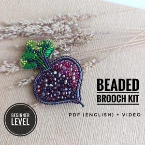 Puede incluir: Un kit de broche de cuentas con forma de remolacha, elaborado con cuentas facetadas de color púrpura oscuro y rojo, acentuado con hojas de lentejuelas verde brillante. El texto dice BEADED BROOCH KIT, BEGINNER LEVEL y PDF (ENGLISH) + VIDEO.