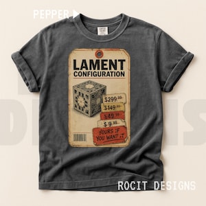 May include: A charcoal grey short-sleeve t-shirt featuring a graphic of a puzzle box and the text LAMENT CONFIGURATION. The design includes a price list with values $299.99, $149.99, $49.99, $9.99 and the text YOURS IF YOU WANT IT on a tag.