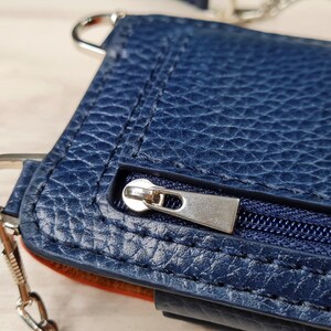May include: A dark blue leather purse with a silver zipper and a silver chain strap.
