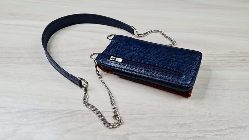 May include: A blue leather crossbody phone bag with a silver chain strap. The bag has a zippered pocket and a flap closure.