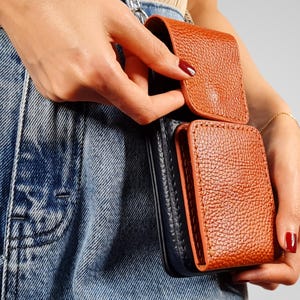May include: A brown leather wallet with a black leather flap. The wallet is attached to a belt loop.