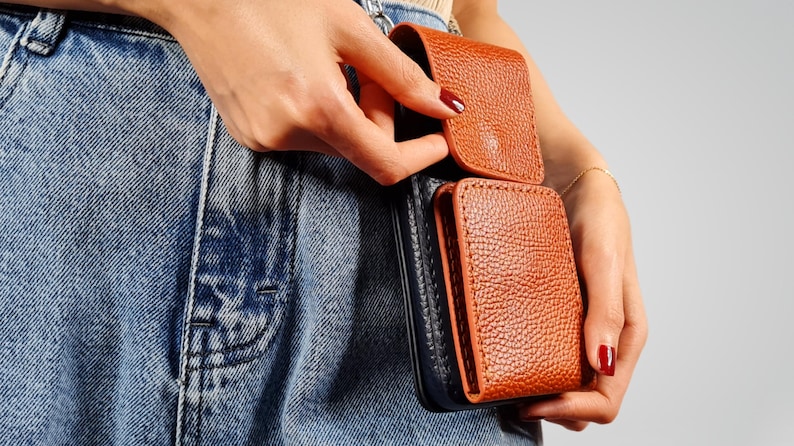 May include: A brown leather wallet with a black leather flap. The wallet is attached to a belt loop.