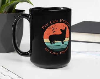 Może przedstawiać: Czarny ceramiczny kubek z uchwytem. Kubek ma wzór retro z napisem "I've Got Friends In Low Places" i sylwetką psa corgi w okrągłym wzorze z pomarańczowymi, turkusowymi i niebieskimi paskami.