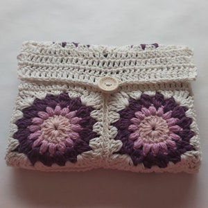 May include: A white crocheted pouch with a purple and pink floral design. The pouch has a button closure with the text "Handmade with Love".