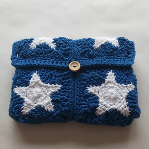 May include: Blue crocheted clutch with white star designs and a wooden button that says "Handmade with Love".