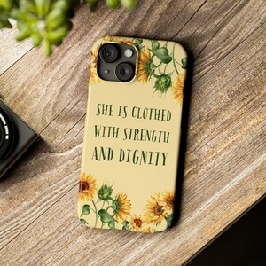 May include: A yellow and green phone case with a floral design and the text "She is clothed with strength and dignity".