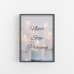 Puede incluir: Una impresión enmarcada con una imagen borrosa de velas y el texto "Never Stop Praying" en fuente cursiva negra.