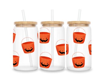 Op de afbeelding: Drie glazen glazen met bamboe deksels en rietjes. Elke beker heeft een Halloween-thema met oranje pompoen-emmers met glimlachende gezichten.
