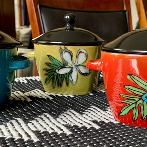 May include: Three ceramic soup tureens with lids. The tureens are decorated with floral designs. The tureens are blue, green, and red.