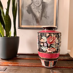 Peut inclure: Un grand vase en porcelaine rouge et noir avec un motif floral. Le vase a une large ouverture et une base étroite. Il est décoré d'accents dorés et de diverses fleurs, notamment des roses, des pivoines et des chrysanthèmes.