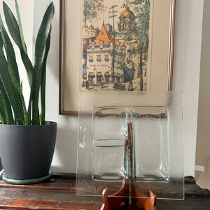 Peut inclure: Un plat de service en verre transparent avec quatre sections, présenté sur un support en bois. Le plat a une surface texturée et est parfait pour servir des amuse-gueules ou des en-cas.