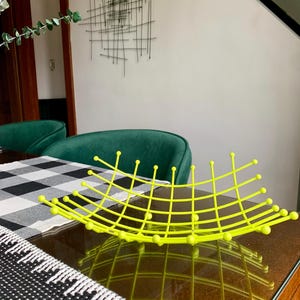 Peut inclure: Un bol décoratif vert citron vif doté d'une structure en forme de grille avec de petites pointes sphériques à chaque intersection. Le bol présente un design incurvé à cadre ouvert créant un motif géométrique, offrant une touche de couleur.