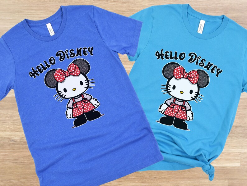 May include: Two blue and turquoise t-shirts with a Hello Disney graphic featuring a cartoon character with red polka dot bow and red polka dot dress.