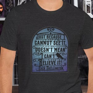 Pode incluir: Uma camiseta cinza escuro mesclada com um gr&aacute;fico de um port&atilde;o de estilo g&oacute;tico com um corvo e o texto "Just because I cannot see it, doesn't mean I can't believe it! Jack Skellington"