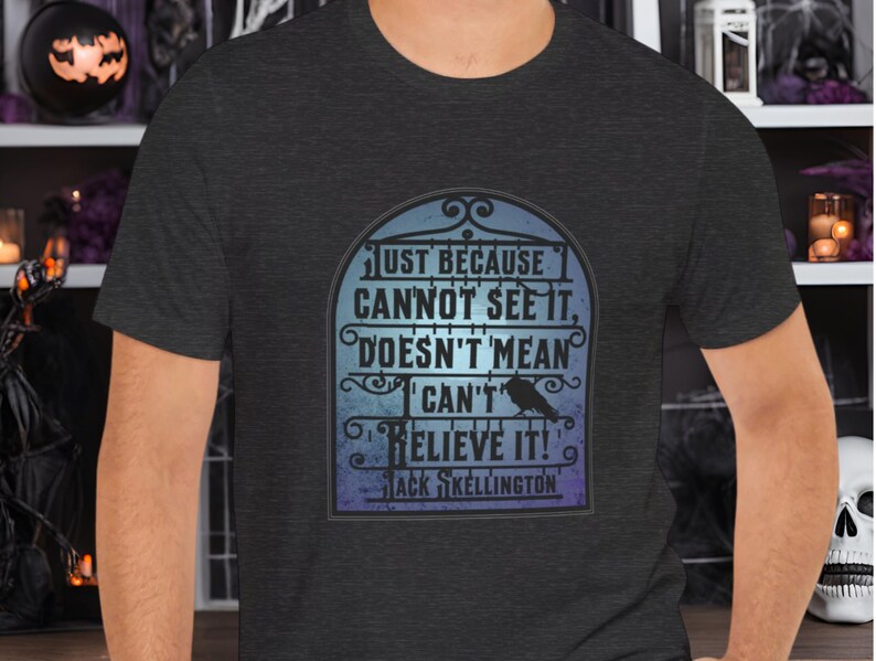 Pode incluir: Uma camiseta cinza escuro mesclada com um gr&aacute;fico de um port&atilde;o de estilo g&oacute;tico com um corvo e o texto "Just because I cannot see it, doesn't mean I can't believe it! Jack Skellington"