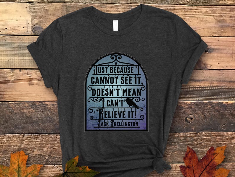 Pode incluir: Uma camiseta cinza escura com uma estampa gr&aacute;fica de um p&aacute;ssaro preto em uma gaiola. O texto na estampa diz "Just because cannot see it, doesn't mean can't believe it!" e "Jack Skellington".