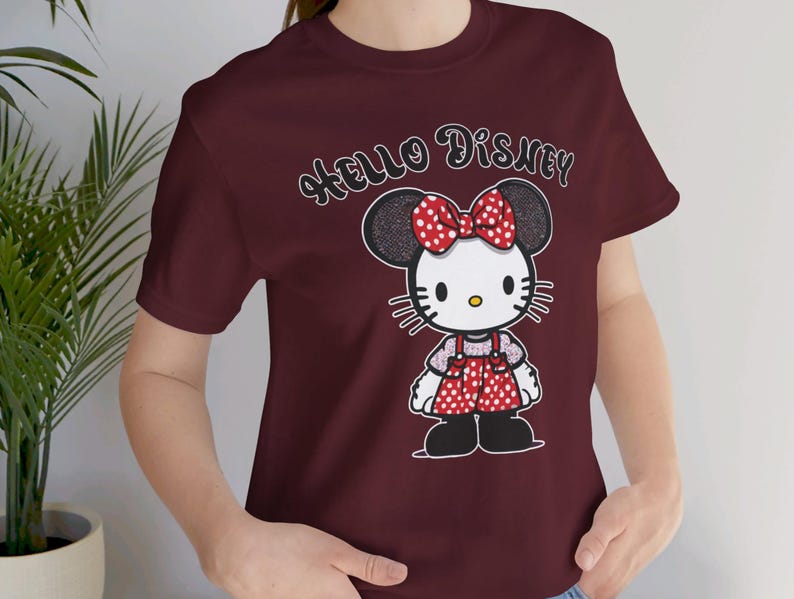 May include: Burgundy t-shirt with a cartoon image of Hello Kitty wearing a red and white polka dot dress and a bow. The text "Hello Disney" is printed on the shirt.