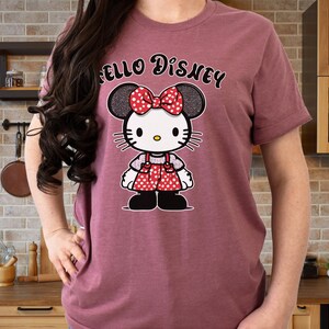 May include: A maroon t-shirt with the text "Hello Disney" printed on the front. A cartoon image of a character with black and white polka dot ears and a red and white polka dot dress is printed below the text.