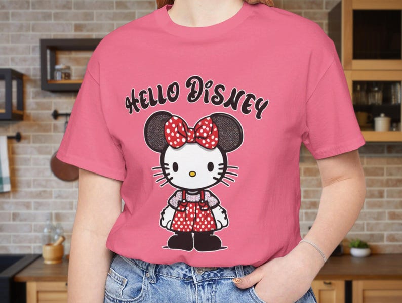 May include: Pink t-shirt with a black and white cartoon image of Hello Kitty wearing a red bow and a red and white polka dot dress. The text "Hello Disney" is printed in black on the shirt.