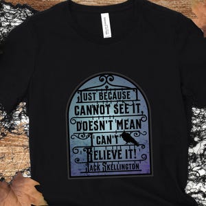 Pode incluir: Camiseta preta com um gr&aacute;fico de um port&atilde;o com o texto "JUST BECAUSE CANNOT SEE IT, DOESN'T MEAN CAN'T BELIEVE IT!" e "JACK SKELLINGTON" abaixo.