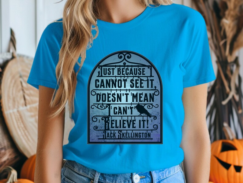 Pode incluir: Uma camiseta azul turquesa com uma estampa gr&aacute;fica em preto e branco de uma cita&ccedil;&atilde;o dentro de uma moldura decorativa. A cita&ccedil;&atilde;o diz "Just because cannot see it, doesn't mean I can't believe it!" com o nome "Jack Skellington" na parte inferior.