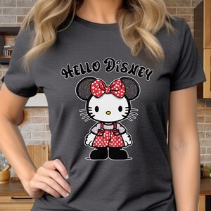 May include: A dark gray t-shirt with the text "Hello Disney" printed in white. A cartoon image of a red and white polka dot Minnie Mouse with a bow is centered on the shirt.