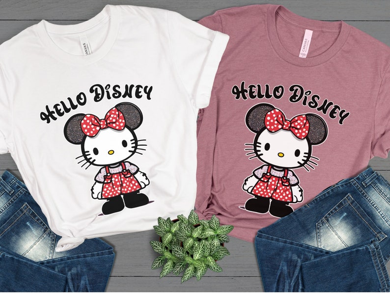 May include: Two t-shirts with a Hello Disney graphic featuring a Hello Kitty character with Minnie Mouse ears and a red polka dot bow. The t-shirts are white and pink.